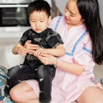 A joyful mother and son bonding over wooden toys in their home.